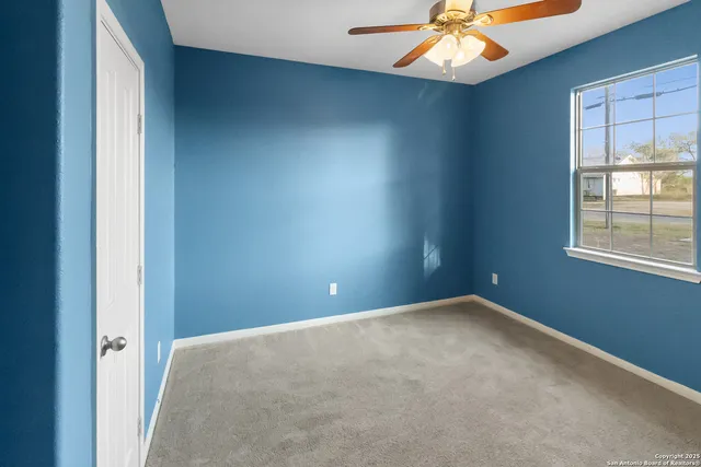 an empty room with windows and chandelier fan