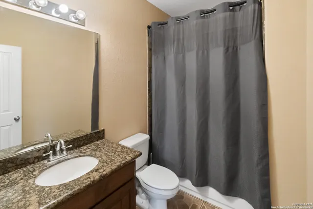 a bathroom with a granite countertop sink toilet and a mirror