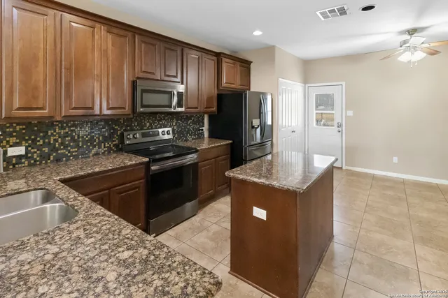 a kitchen with stainless steel appliances granite countertop a stove a sink and a microwave