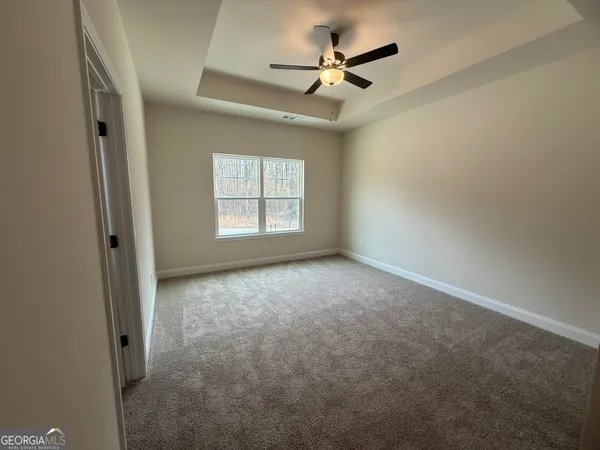 an empty room with windows and fan