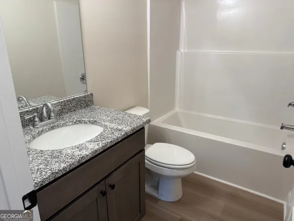 a bathroom with a granite countertop sink toilet and a bathtub