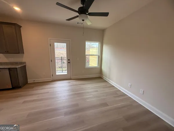 an empty room with wooden floor fan and windows