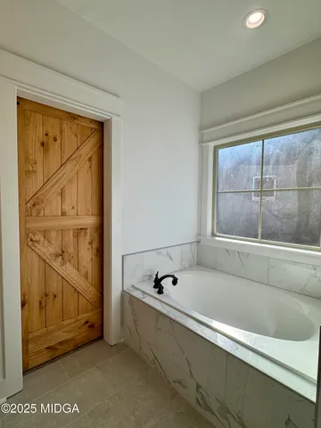 a bathroom with a bathtub and next to a window