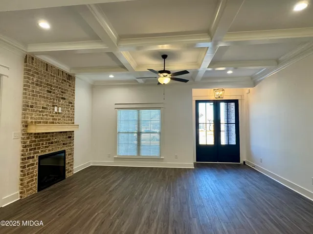 a view of an empty room with wooden floor fireplace and a window
