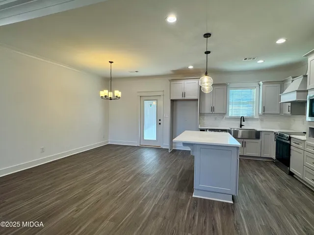an open kitchen with wooden floor and stainless steel appliances