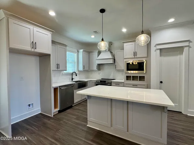 a large kitchen with kitchen island a stove a sink a center island and wooden floor