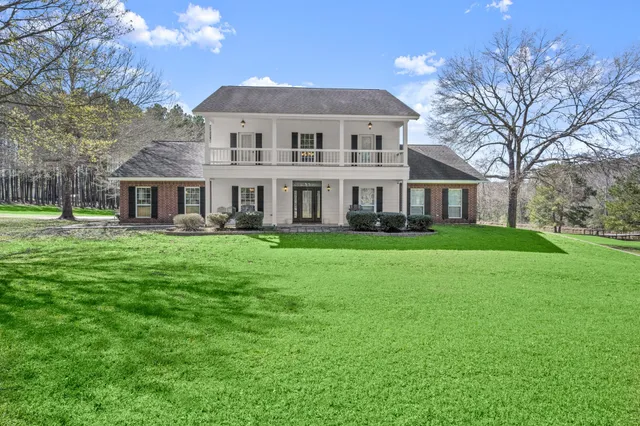 a front view of a house with a garden and trees