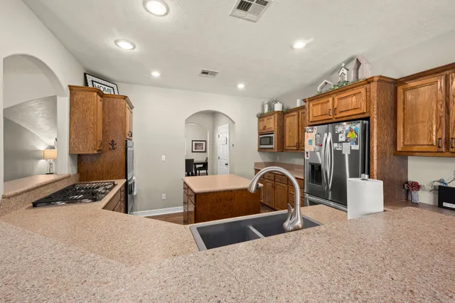 a large kitchen with sink a counter top space and stainless steel appliances