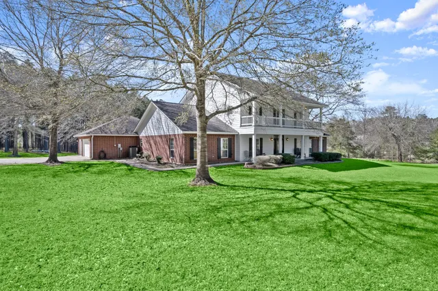 a view of a house next to a big yard with large trees