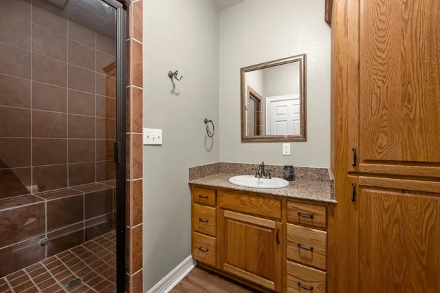 a bathroom with a granite countertop sink a mirror and a shower
