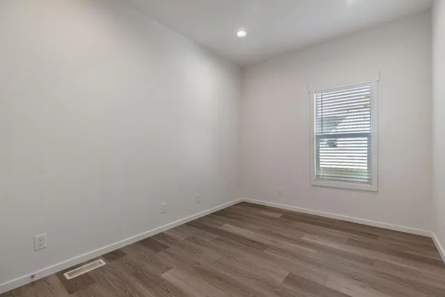an empty room with wooden floor and white walls