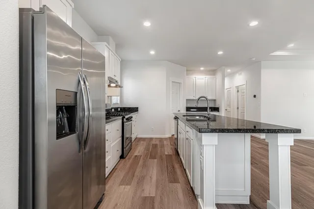 a kitchen with granite countertop a sink stainless steel appliances and cabinets
