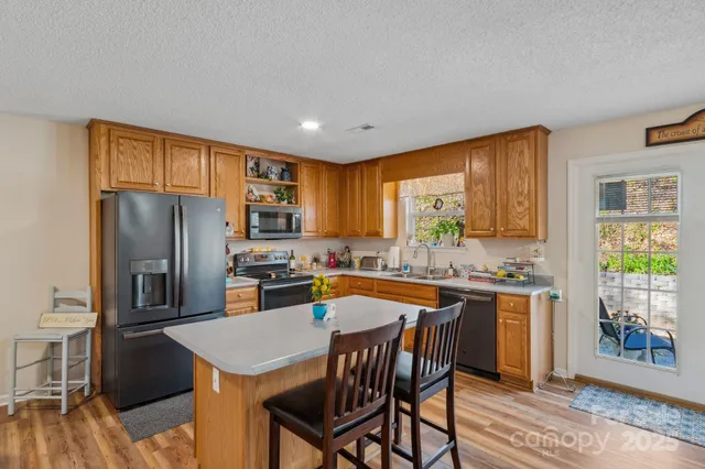 a kitchen with stainless steel appliances granite countertop a stove a refrigerator a sink a stove and island with wooden floor