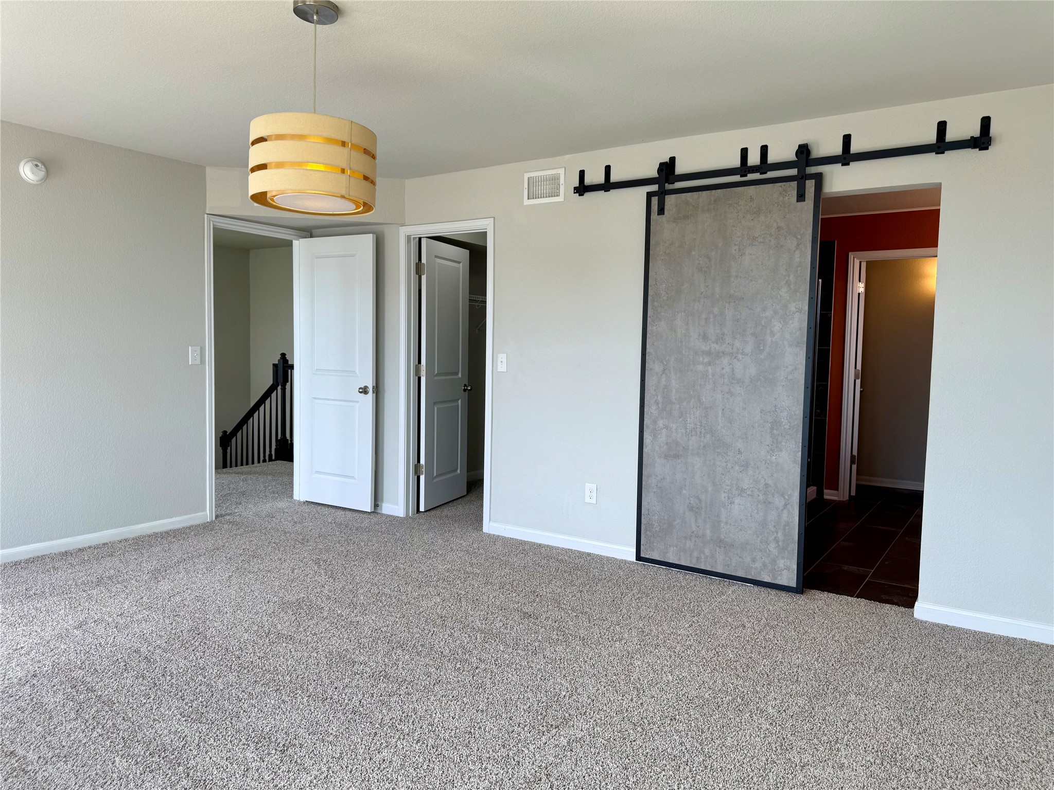 1293 Nevarez Kyle, TX 78640 - Photo 16 of 31 Another view of the Primary bedroom featuring carpet flooring, visible vents, baseboards, and a barn door