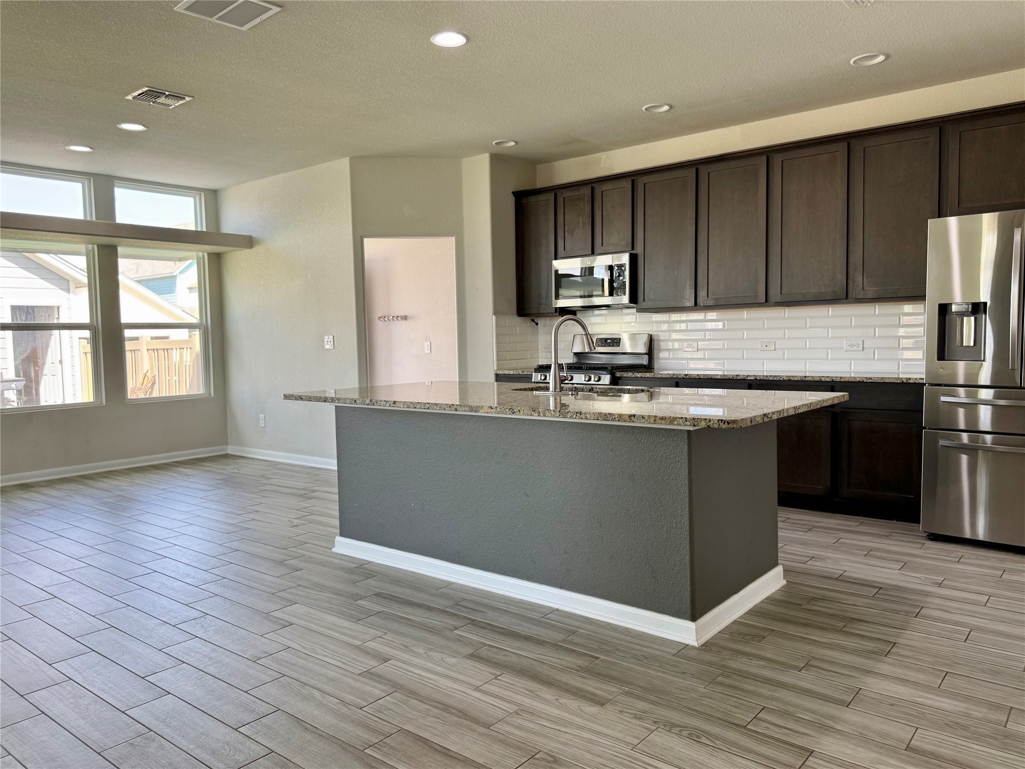 1293 Nevarez Kyle, TX 78640 - Photo 6 of 31 Kitchen featuring a sink, light stone counters, stainless steel appliances, and dark brown cabinetry