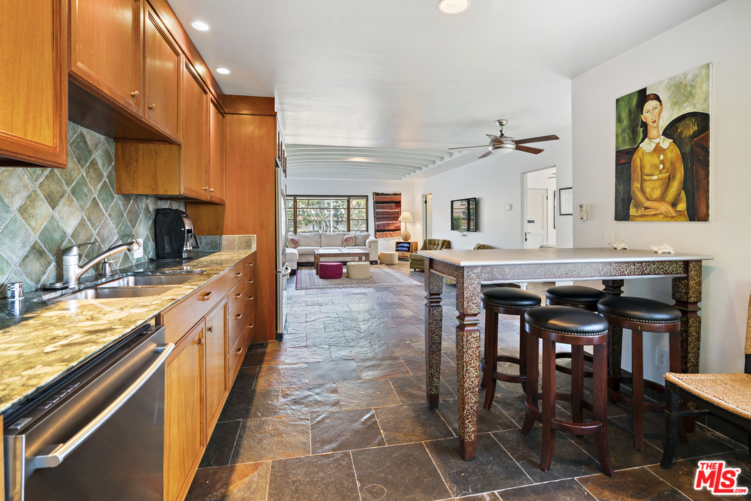 23746 Malibu Road Malibu, CA 90265 - Photo 36 of 46 a kitchen with stainless steel appliances granite countertop a stove top oven a sink a dining table and chairs with wooden floor