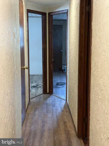 an empty room with wooden floor chandelier and windows