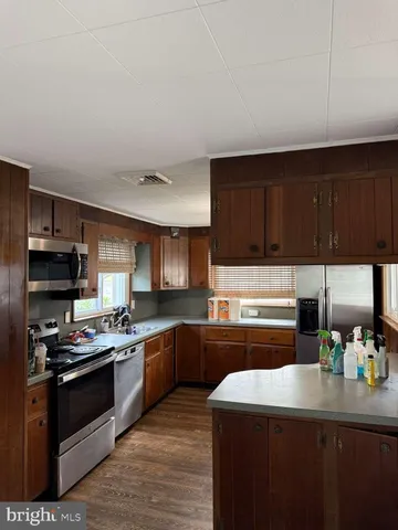 a kitchen with kitchen island granite countertop a sink cabinets and stainless steel appliances