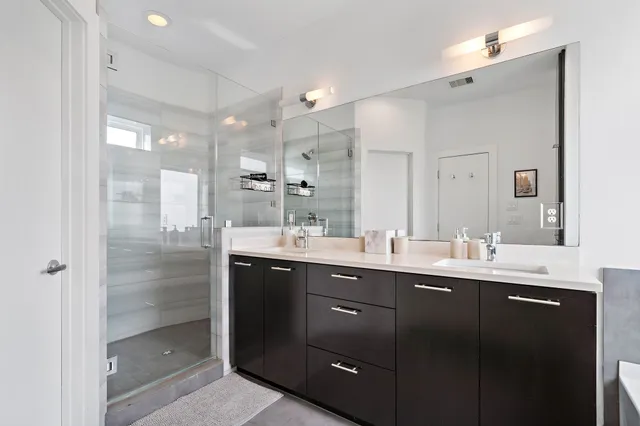 a bathroom with a double vanity sink mirror and shower