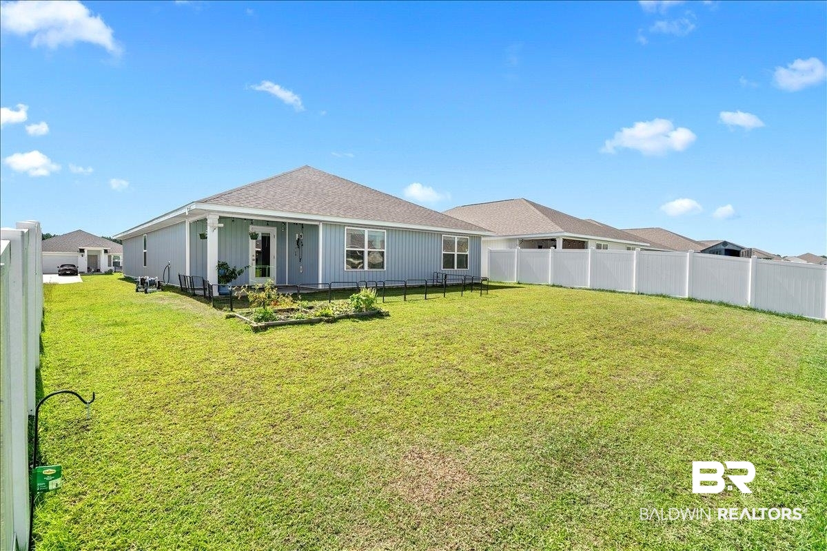 23641 Unbridled Loop Daphne, AL 36526 - Photo 28 of 40 Expansive rear yard featuring a manicured lawn, white privacy fencing, and a covered back patio