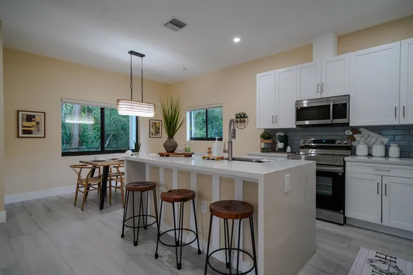 a kitchen with stainless steel appliances a table chairs sink and microwave