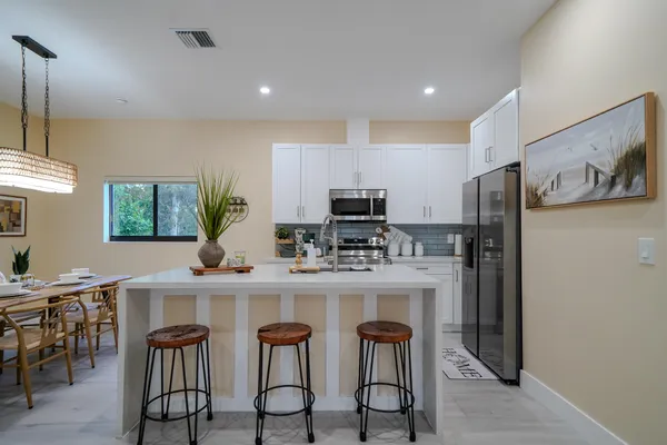 a kitchen with stainless steel appliances a table chairs refrigerator and microwave