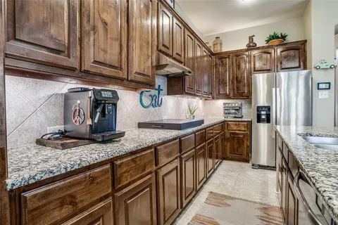 a kitchen with granite countertop a sink a stove and refrigerator