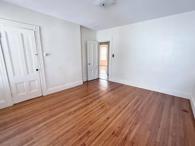 a view of an empty room with wooden floor and entryway