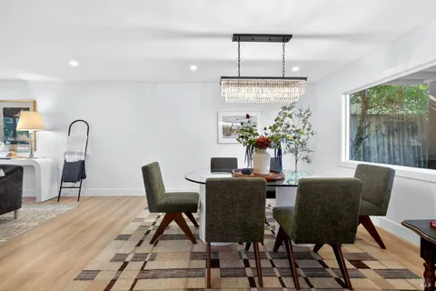 a kitchen with stainless steel appliances granite countertop a stove top oven a sink dishwasher and white cabinets with wooden floor