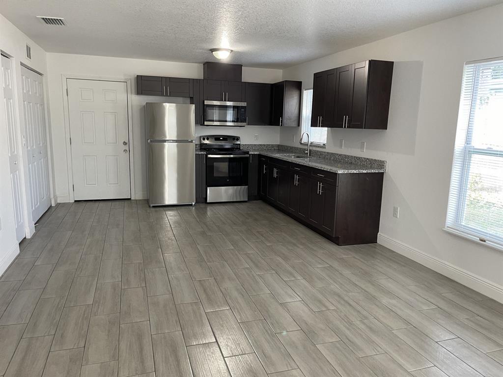 9835 Gray Fox Lane Port Richey, FL 34668 - Photo 17 of 17 a kitchen with stainless steel appliances wooden floors and wooden cabinets