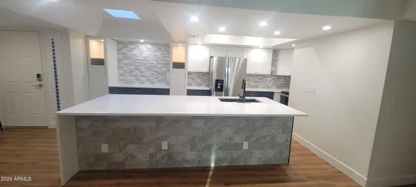 a view of a kitchen with a refrigerator a sink and a large mirror