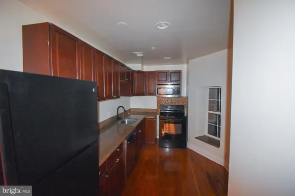 a kitchen with granite countertop a refrigerator a sink and wooden cabinets