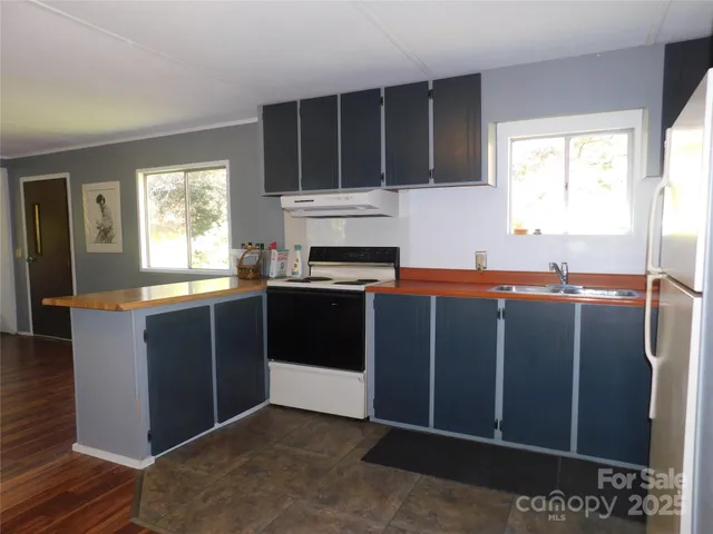 a kitchen with stainless steel appliances granite countertop a refrigerator a sink dishwasher a stove with wooden cabinets and floor