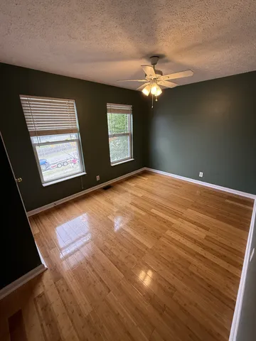 an empty room with windows and fan