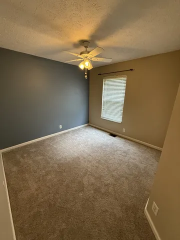 an empty room with a chandelier fan and windows
