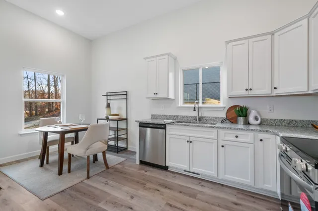 a kitchen with granite countertop a sink cabinets and wooden floor