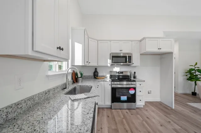 a kitchen with granite countertop a stove sink and cabinets