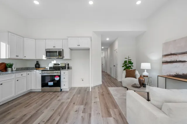 a living room with stainless steel appliances furniture a couch and a kitchen view