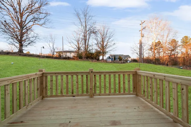 a view of a deck with a big yard and large trees