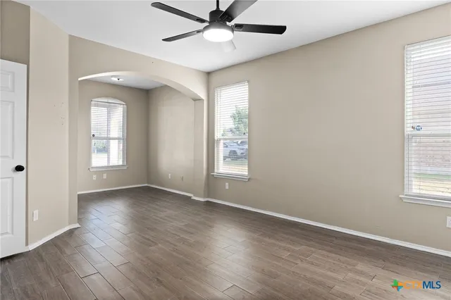 a view of an empty room with a window and wooden floor