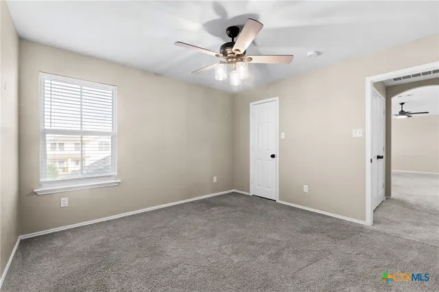 an empty room with windows and fan