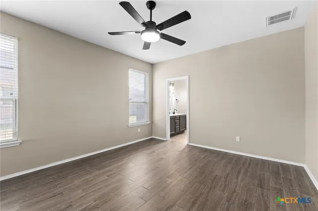 an empty room with wooden floor and windows