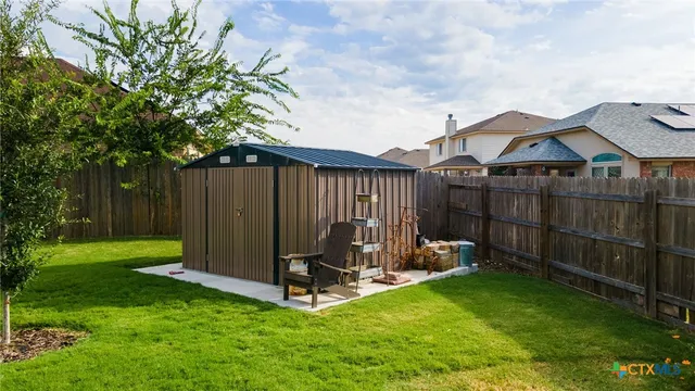 a view of a chair and table in backyard of the house