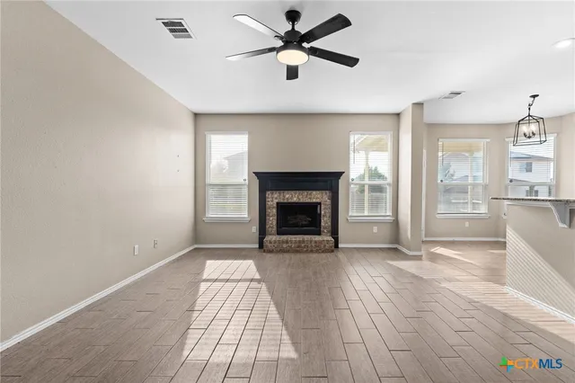 a view of a livingroom with a fireplace a ceiling fan and hardwood floor