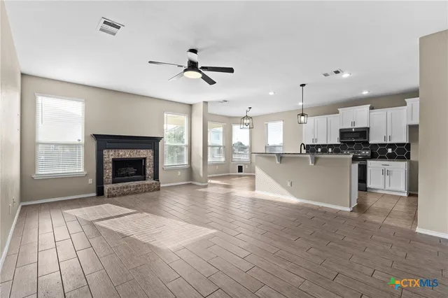 a large kitchen with granite countertop a stove top oven a sink dishwasher and a fireplace with wooden floor