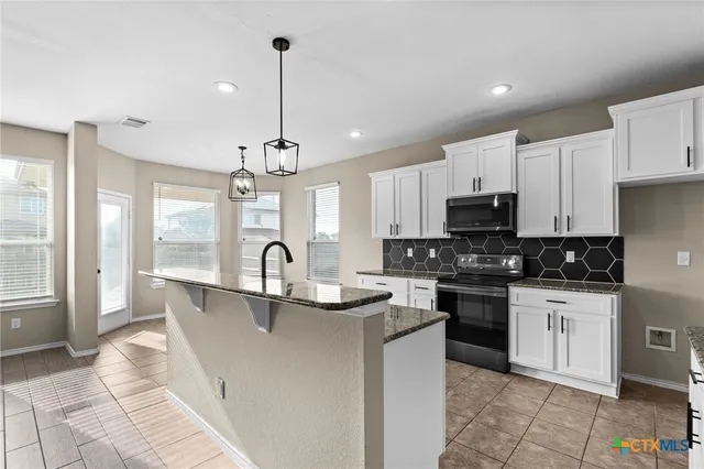 a kitchen with stainless steel appliances granite countertop a sink a stove top oven a counter space and cabinets