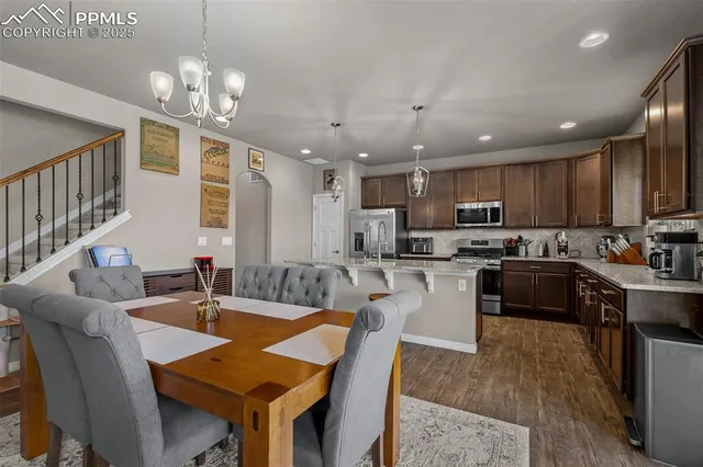 a kitchen with a dining table chairs stainless steel appliances and cabinets