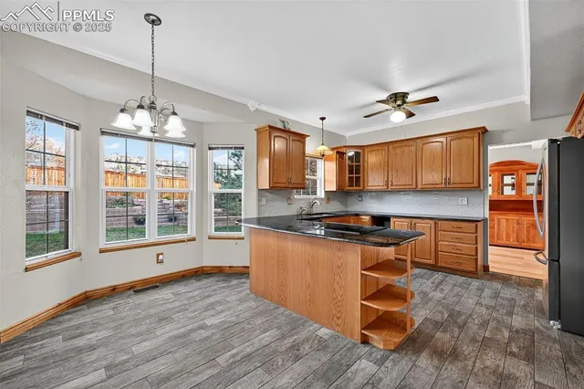 a kitchen with stainless steel appliances granite countertop a stove a sink dishwasher and a flat screen tv with wooden floor