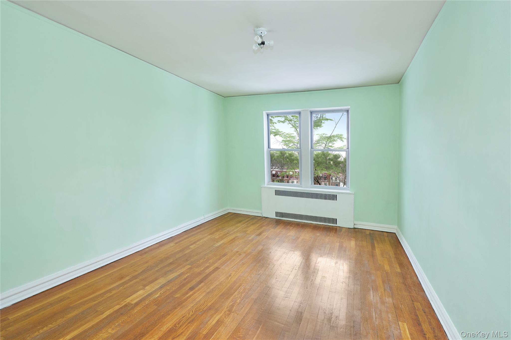 75-40 Austin Street, Unit 5 Queens, NY 11375 - Photo 2 of 12 a view of an empty room with wooden floor and a window