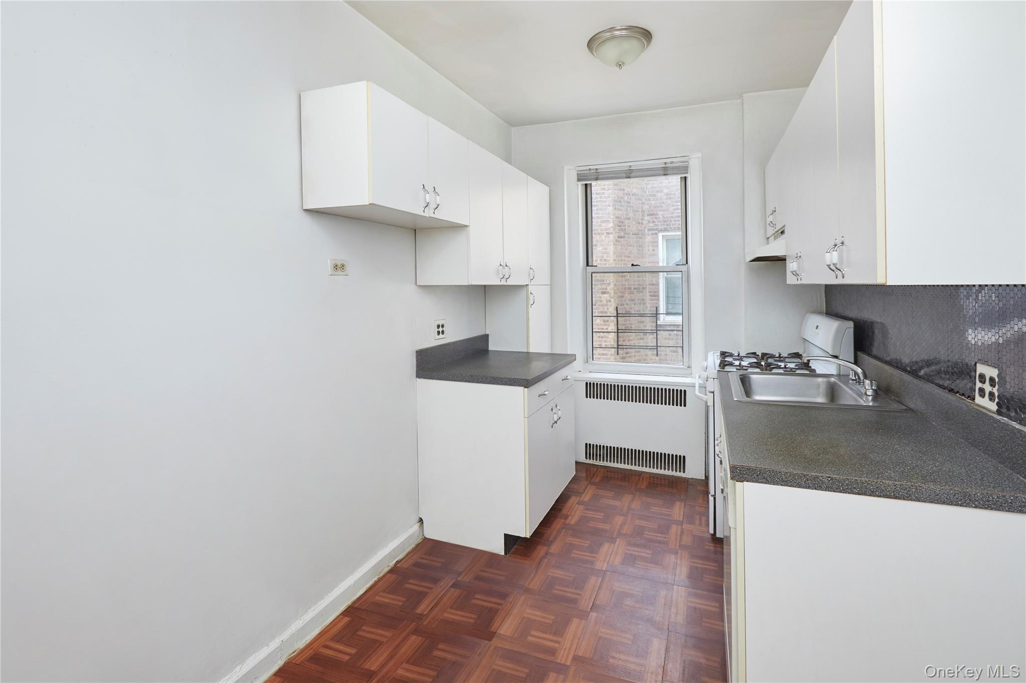 75-40 Austin Street, Unit 5 Queens, NY 11375 - Photo 9 of 12 a kitchen with granite countertop a sink stove and cabinets